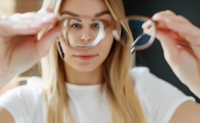 modelfoto af ung kvinde der kigger gennem det ene glas på et par meget stærke briller